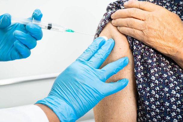 Elderly Asian senior woman getting covid-19 or coronavirus vaccine by doctor make injection. - Valokuva, kuva