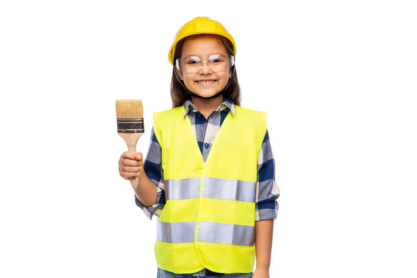 girl in helmet and safety vest with paint brush - Foto, Imagen
