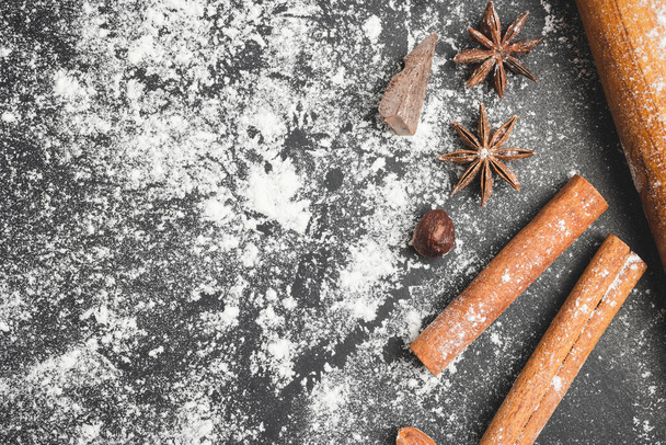 Baking concept, rolling pin, star anise, nuts, cinnamon stick and piece of chocolate on a dark background, prepare for cooking, top view. - Foto, Imagem