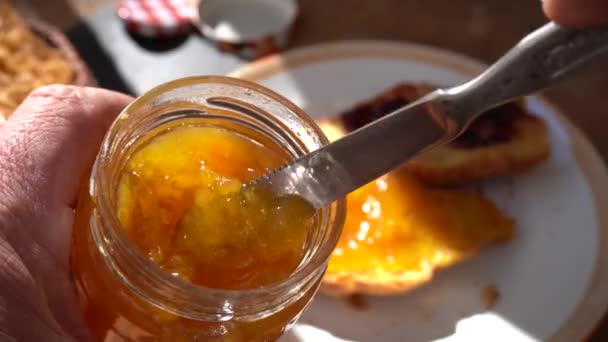 Nůž míchající broskvovou marmeládu ve skleněné sklenici - Záběry, video