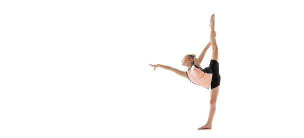 Little flexible girl, rhythmic gymnastics artist isolated on white studio background. Grace in motion, action. Doing exercises in flexibility. - Фото, зображення