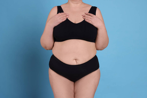 Overweight woman in underwear on light blue background, closeup - Photo, image