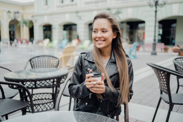 a young confident woman drinks delicious takeaway coffee in a pa - Фото, изображение