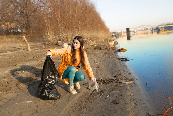 Teenager picking up the trash from a beach - Fotoğraf, Görsel