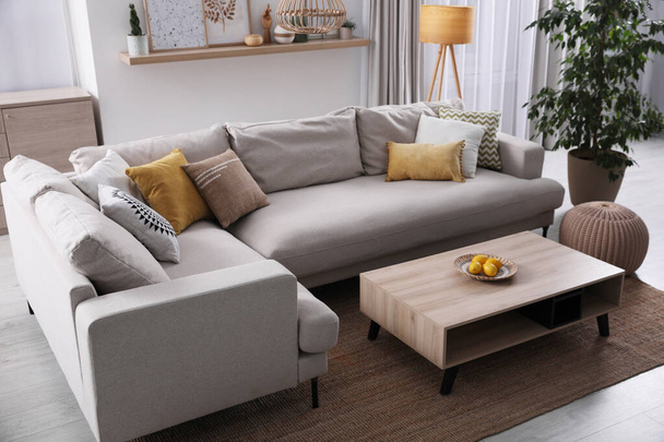 Elegante salón interior con cómodo sofá gris y mesa de centro - Foto, Imagen