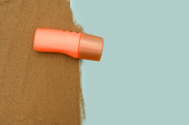 Оранжевый контейнер с защитным солнцезащитным кремом. На песке. Концепция моря. - Фото, изображение