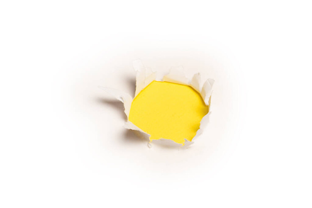 A hole in a white paper on a yellow background, copy space.  - Foto, Imagem