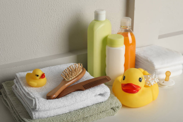 Bathroom towels, toy and baby accessories on white table - Zdjęcie, obraz