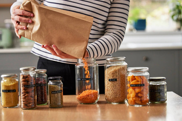 Woman Saving On Packaging By Filling Recycled Jars To Store Dried Food At Home - Foto, Imagem