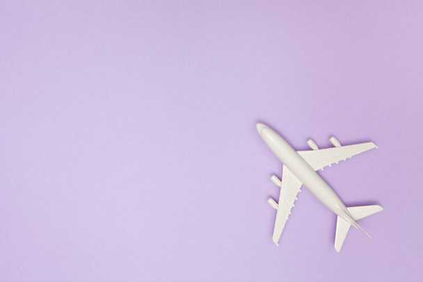 Airplane model. White plane on purple background. Travel vacation concept. Summer background. Flat lay. - Foto, imagen