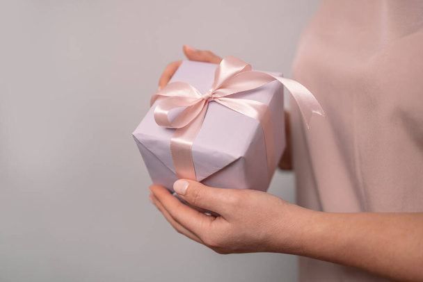Woman holding a small purple gift box in her hands. Valentines day celebration - 写真・画像