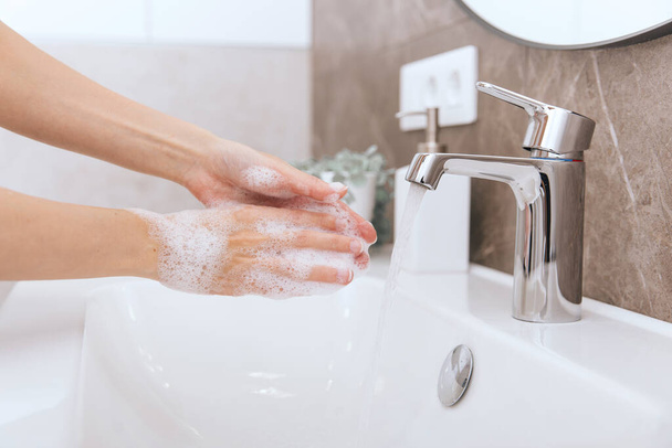 Washing hands under the flowing water tap. Washing hands rubbing with soap for corona virus prevention, hygiene to stop spreading corona virus in or public wash room. Hygiene concept hand detail - Zdjęcie, obraz