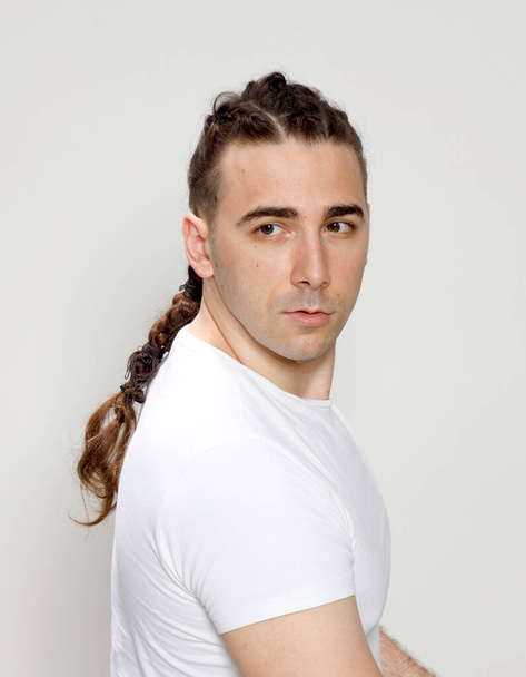 Stylish male model with braids posing in studio on isolated background. Style, hairstyle, fashion concept. - Фото, зображення