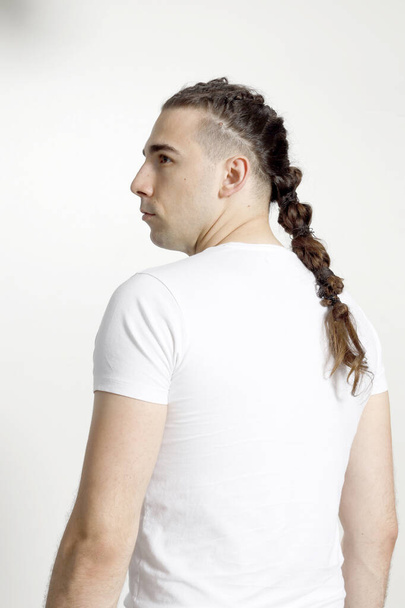 Modèle masculin élégant avec des tresses posant en studio sur fond isolé. Style, coiffure, concept de mode. - Photo, image