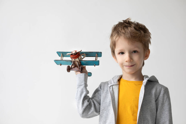 Happy boy play with wooden airplane in hand, child dreams about traveling. Happiness and freedom concept. - Photo, image