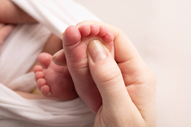 Mamá está haciendo masajes en su pie de bebé. Primeros pies de bebé en las manos de la madre. Prevención de pies planos, desarrollo, tono muscular, displasia. Conceptos de familia, amor, cuidado y salud. Estudio macro. - Foto, imagen