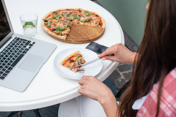 Вид зверху на ділову жінку, яка їсть піцу під час роботи в ресторані піци
 - Фото, зображення