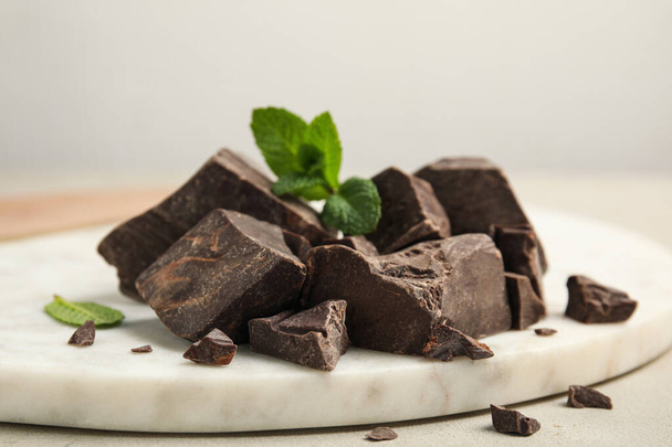 Tasty dark chocolate pieces with mint on white board, closeup - Foto, Imagen
