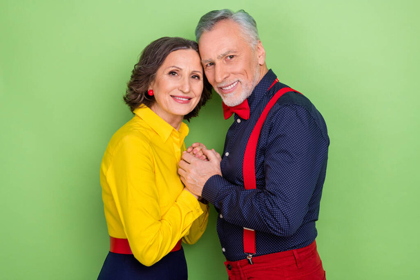 Profile portrait of two aged partners hold hands beaming smile look camera isolated on green color background - Valokuva, kuva