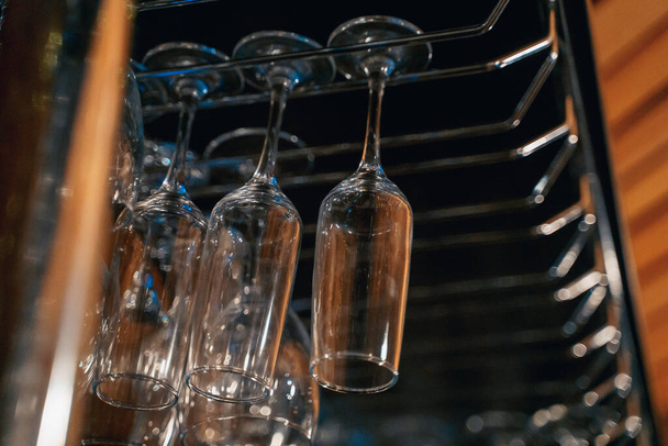 transparent glasses for drinks hang on the bar, nightlife, order - Foto, afbeelding