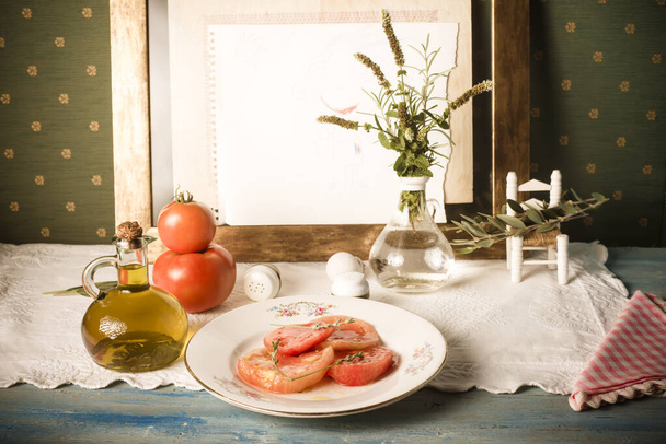  Только томатный салат, нарезанный натуральный помидор и оливковое масло на потрепанном столе. - Фото, изображение