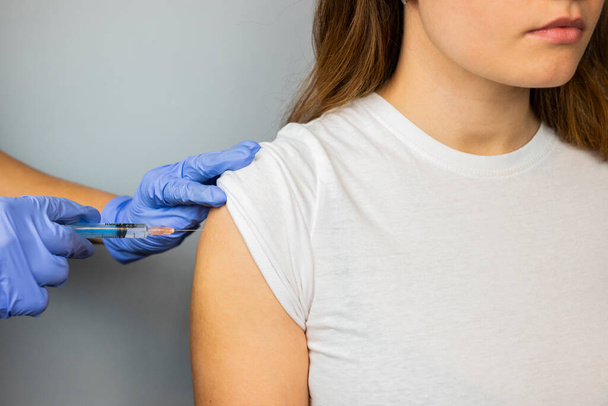 un médecin en gants met un vaccin sur une fille avec une seringue avec une injection - Photo, image