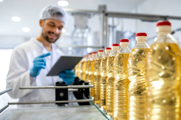 Close up view of industrial vegetable oil production and bottles filled with sunflower oil being transporter on automated conveyor machine. - Photo, Image