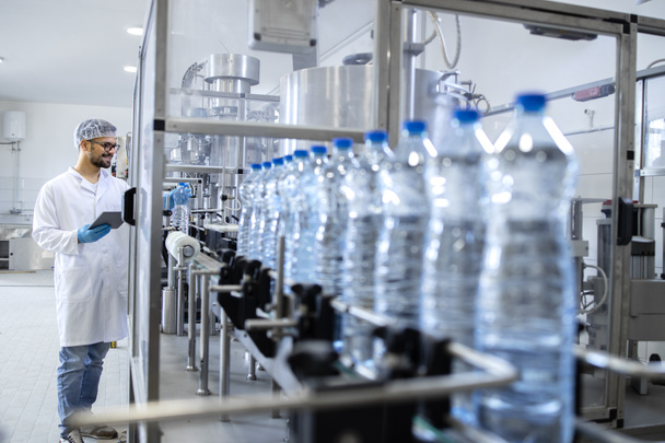 Produzione di acqua gassata in bottiglia. Un tecnologo esperto che fa il controllo di qualità in fabbrica di imbottigliamento. - Foto, immagini