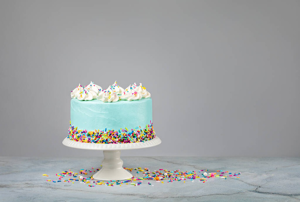 Pastel de cumpleaños azul con coloridas salpicaduras sobre un fondo gris claro. - Foto, imagen