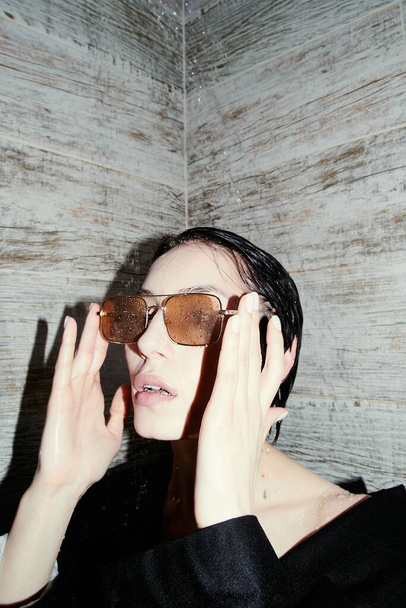 Asian girl in the shower. Black suit. Short wet hair. Yellow eyeglasses. Beautiful eyes and lips. Sexy, young, crazy and cool. Clean white skin. Nice shape. Good quality. Flashlight. Modern and stylish. Fashionable. - Photo, image