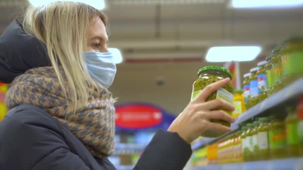 Una mujer elige guisantes enlatados en un supermercado. Compras en la tienda. - Metraje, vídeo
