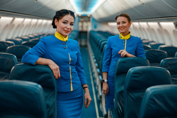 Веселые стюардессы, стоящие в салоне самолетов - Фото, изображение