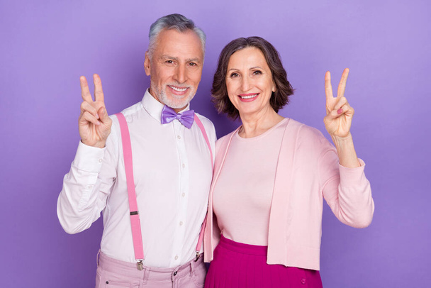 Portrait of two positive cheerful persons fingers demonstrate v-sign isolated on purple color background - Photo, Image