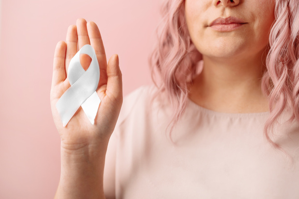 Bewusstseinskampagne für psychische Gesundheit. Frau hält weiße Schleife auf isoliertem pastellrosa Hintergrund zur Unterstützung von Menschen, die leben und krank sind. - Foto, Bild