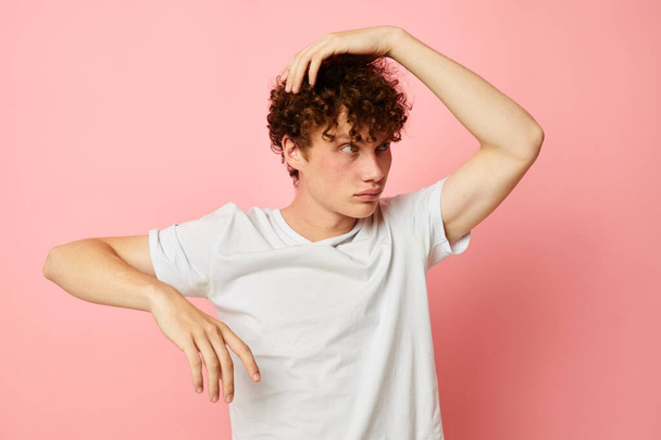 portrait of a young curly man in white t-shirt casual wear emotions pink background unaltered - Fotoğraf, Görsel