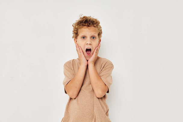 Cheerful boy in beige T-shirt emotions posing light background - Photo, Image