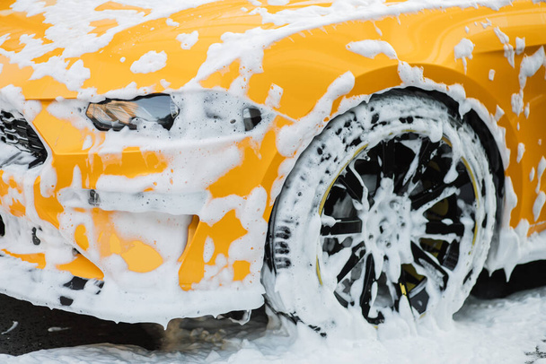 Cropped image of wheel of luxury yellow car in outdoors self service car wash - Fotoğraf, Görsel