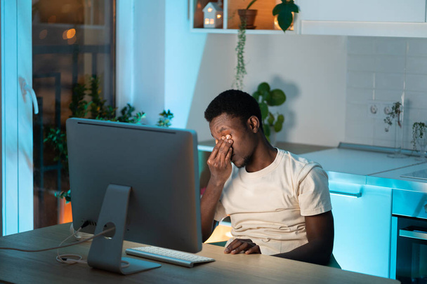 Homem africano sobrecarregado freelancer sentindo cansaço ocular e fadiga durante o uso prolongado do computador - Foto, Imagem
