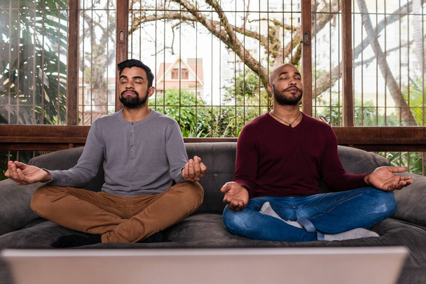 Odaklanmış eşcinsel çift evde birlikte meditasyon yapıyor. - Fotoğraf, Görsel