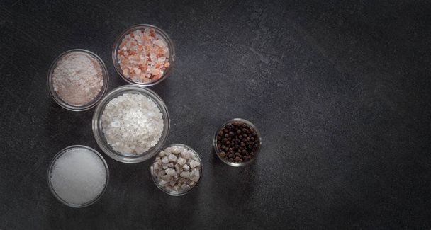 Different types of salt and culinary spices in glass plates on a dark background - Foto, imagen