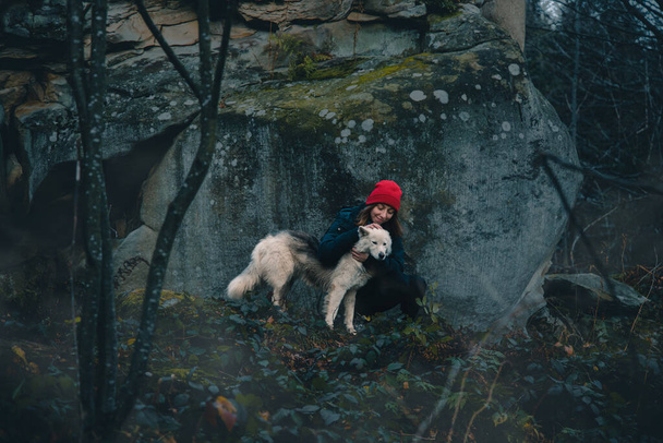 vrouw omhelzen met dier wolf in wandelen reizen door de wildernis hoogland bergen en rotsen van Noord-Europa Scandinavische regio, dramatische landschap mist stijl met rook en koude rotsen overal - Foto, afbeelding