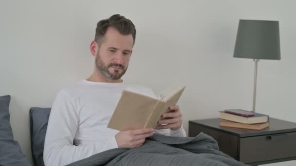 Mann liest Buch im Bett - Filmmaterial, Video