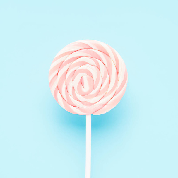 Pink lollipop on a white stick on a light blue background. Flat lay, copy space - Foto, Bild
