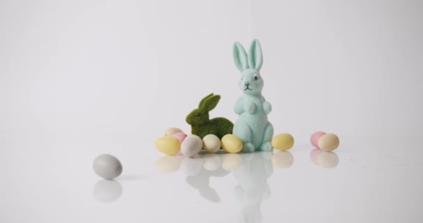 Coelhinhos brinquedos em fundo branco, muitos ovos. Feliz dia de Páscoa. Mensagem de texto - Filmagem, Vídeo