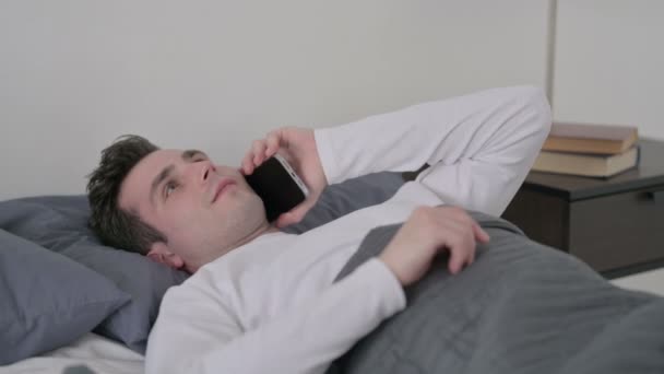 Muž mluví na Smartphone, zatímco spí v posteli - Záběry, video