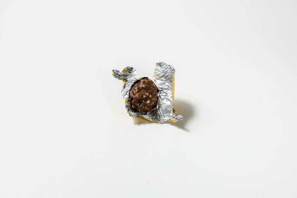 sweet round chocolate nuts candy with torn wrapper on white background. - Photo, Image