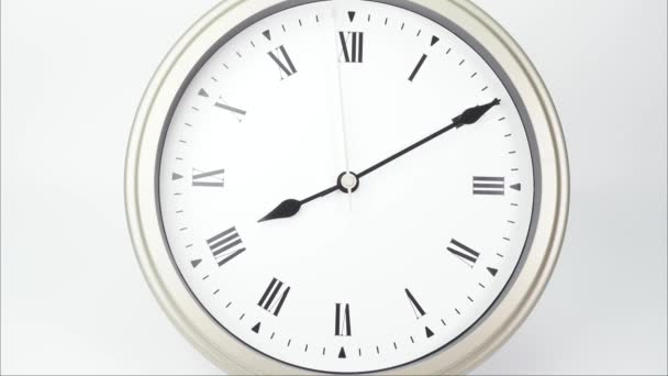 Time lapse zilveren muur klok vertelt de tijd om 9 uur. Toont de snelheid van de tijd op Romeinse cijfers. Op witte achtergrond. - Video