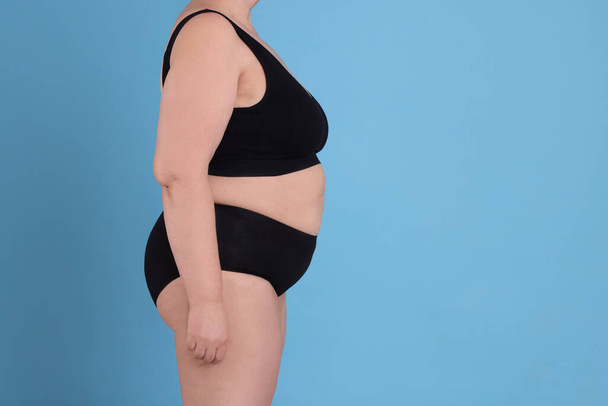 Overweight woman in underwear on light blue background, closeup. Space for text - Foto, Bild