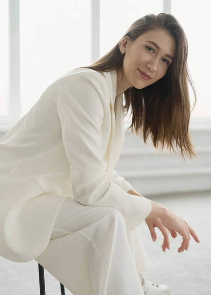 Gorgeous young female in classic white suit. Brunette. European. Neutral background. Elegant and sexy. About women problems and lifestyle. Good for beauty and cosmetology advertising. Healthy and smart lifestyle. - Foto, imagen
