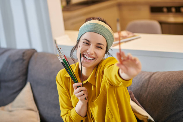 Smiling cute young woman with a palette and brushes in hands - Foto, imagen